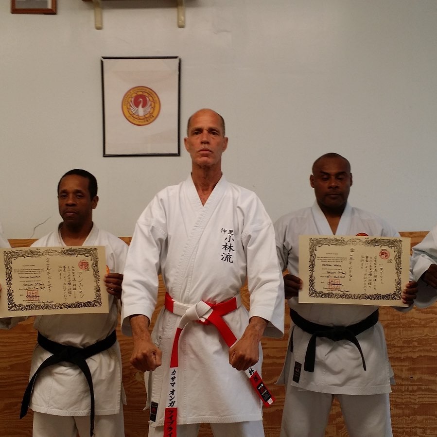 Sensei Kassama with two black belt students holding certificates